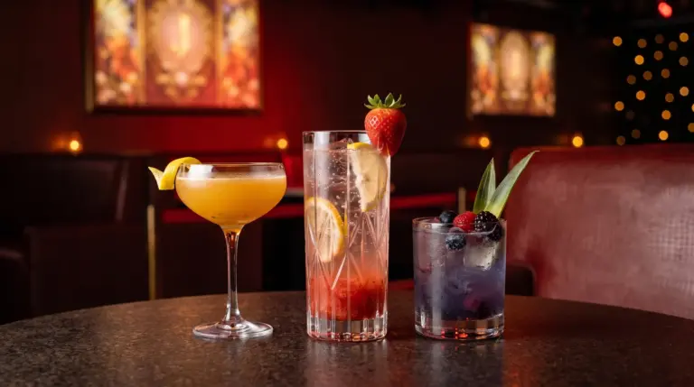 Editorial illustration of strawberry, passion-fruit and blue berry cocktails against burgundy lounge seating