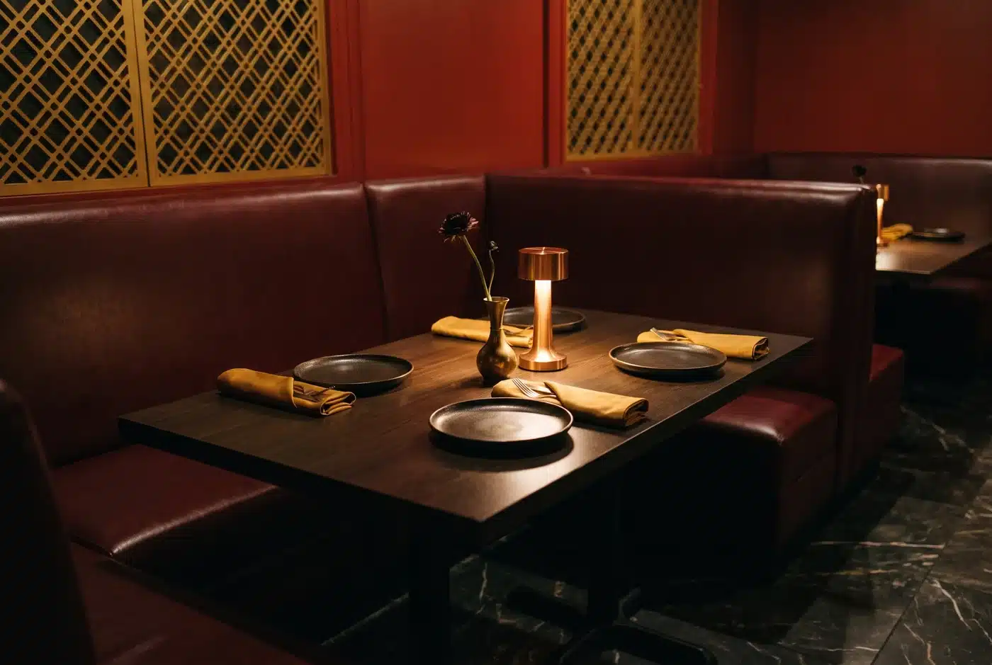 Editorial illustration of a table for two with dark plates, folded napkins and warm lighting
