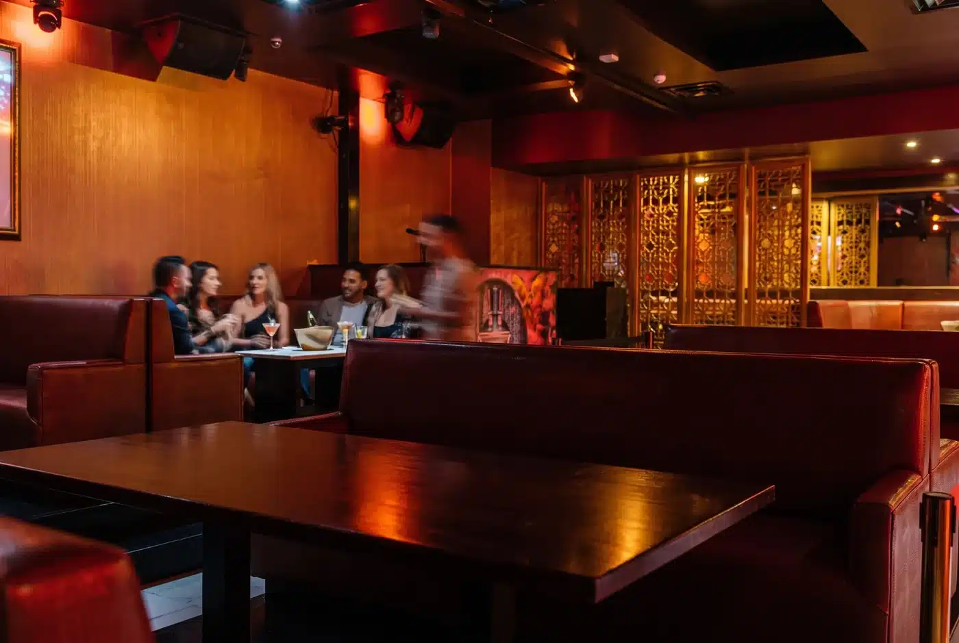 Editorial illustration of warm lounge lighting and adult guests gathering near red booth seating